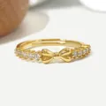 Nahaufnahme eines eleganten vergoldeten Schleifenrings mit funkelnden Zirkonias - Schleifenstil (R1815) / 14K-Gold