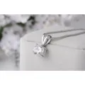 Primo piano dettagliato di una collana con ciondolo solitario rotondo su vassoio grigio. - Diamante bianco