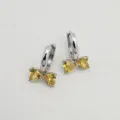 Close-up detail of silver hoop earrings featuring yellow heart-shaped zircon bow design. - Platinum Yellow Zirconia