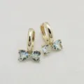 Detail shot of dainty bow hoop earrings featuring sparkling heart-shaped zircon stones in gold. - Gold With Lake Blue Zircon