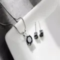 Primo piano di uno splendido set con collana con ciondolo in pietra nera rotonda e orecchini. - Diamante nero