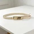 Close-up of a stylish braided thin belt with a shiny gold metal buckle for dresses. - Beige