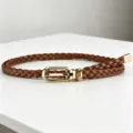 Detailed view of brown braided leather belt with gold metal buckle, stylish accessory. - Brown