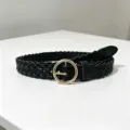 Black braided belt with round gold buckle for women, stylish detailed view of woven leather texture. - Black