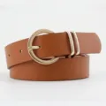Close-up detail shot of brown PU leather belt featuring a classic gold circular pin buckle. - Brown