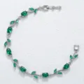 Elegante zilverkleurige armband met smaragdgroene stenen in een blad- en rankontwerp. - Zilveren Groene Edelsteen