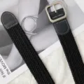 Woven elastic belt detail shot showing textured black fabric and sturdy silver metal buckle. - Black