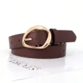 Close-up detail of retro oval gold buckle on a brown faux leather belt for women - Coffee