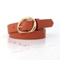 Detailed shot of retro oval gold buckle on a brown faux leather women's belt - Orange