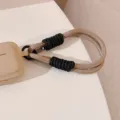 Détail rapproché de la dragonne de téléphone tressée bicolore sur une coque de mobile - Sangle Noire et Café / Carte Transparente