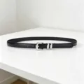 Close-up view of a minimalist black thin leather belt with a polished silver metal buckle. - Black