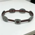 Detailed view of a Western vintage leather belt with ornate silver carved concho plates - Coffee