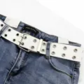 Close-up detail of a white double-row grommet belt styled with blue denim jeans - One Size 100cm / White