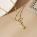 Detail of a minimalist gold-plated arrow pendant on a classic box chain necklace. - Arrow