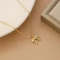 Close-up of elegant gold-plated bow pendant necklace with sparkling stones - Bow