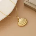Detailed macro view of a glossy gold-plated shell pendant on a delicate box chain. - Shell