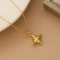 Detail view of a gold-plated star pendant necklace with a central crystal accent - Domed Four-Pointed Star