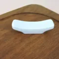 White curved melamine chopstick rest holder displayed on a rustic wooden board. - Milky White