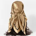 Detailed view showing the texture of a gold polka dot satin scarf tied as a headscarf. - 90x90cm / S Polka Dot-Gold