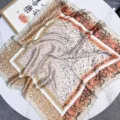 Close-up of a stylish leopard print silk-like satin square scarf on a white marble table - 70*70cm / Beige