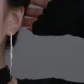 Gros plan sur d'élégantes boucles d'oreilles longues à pampilles en argent sur modèle - Boucles d'Oreilles Traversantes Gland Cylindrique