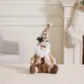 Handmade brown and khaki Christmas gnome plush doll sitting on a mantle for holiday decor - Sitting Santa Claus