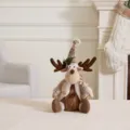 Cute plush reindeer Christmas ornament with knitted hat and scarf sitting on a table - Sitting Reindeer