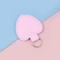 Herzförmiger rosa Leder-Schlüsselanhänger mit silbernem Ring auf pastellfarbenem Grund - Rosa
