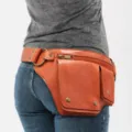 Riñonera vintage de cuero marrón con múltiples bolsillos, usada en la cadera sobre jeans - Estilo Liso / Marrón