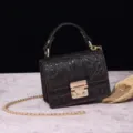 Detalle de un bolso vintage marrón con textura de cocodrilo y cierre metálico dorado. - Café (PG877 Café)