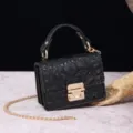 Detalle de primer plano de bolso negro de cocodrilo con un elegante cierre de metal dorado - Negro (PG877 Negro)
