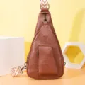 Detalle de un bolso bandolera de cuero PU marrón con una elegante correa ancha estampada. - Marrón