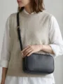 Bolso bandolera chic de cuero negro llevado por una modelo para un look diario elegante - Negro