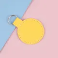 Porte-clés rond en cuir jaune avec surpiqûres blanches sur un fond bicolore pastel - Jaune Vif