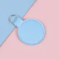 Porte-clés rond en cuir bleu clair élégant avec anneau argenté sur fond pastel - Bleu Perle