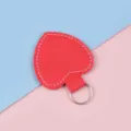 Roter herzförmiger Leder-Schlüsselanhänger mit weißer Naht auf blau-rosa Grund - Rot