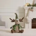 Plush Christmas reindeer doll with green hat and vest in a cozy fireplace setting - Sitting Christmas Reindeer (Pointed Hat) / Mallow Green