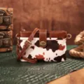 Close-up of a vintage Western cow print crossbody bag featuring gold-tone twist lock hardware - Cow Brown (PG5051)