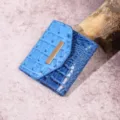 Cartera azul con patrón de cocodrilo, diseño de tres pliegues y detalle de barra dorada. - Cocodrilo Azul Cielo (PG831)