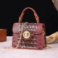 Detailed view of crocodile embossed leather handbag with gold chain strap - Brown + Purple