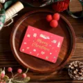 Red Christmas greeting card with gold foil Merry Christmas text and gift icons - Snowman Wreath Style