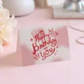Elegant birthday card with red Happy Birthday lettering on a soft pink background. - Style 6