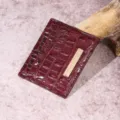 Detalle de cerca de la textura de cuero de cocodrilo burdeos en un tarjetero para mujer - Tarjetero (PG832) / Rojo Uva
