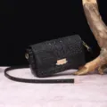 Detalle de bolso negro con relieve de cocodrilo y cierre metálico dorado vintage. - Negro