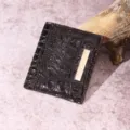 Primo piano di un porta carte marrone scuro con trama a coccodrillo e dettaglio oro. - Portacarte (PG832) / Caffè