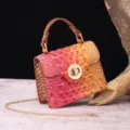 Macro detail of luxury pink gradient crocodile pattern handbag with golden metal chain strap - Pink Orange Gradient
