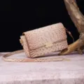 Detalle de la textura de cocodrilo y el cierre dorado en un bolso de hombro beige. - Beige Concha