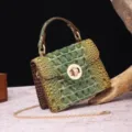 Close-up of vintage green embossed crocodile pattern handbag with gold hardware - Gradient Green + Brown