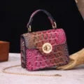 Detail view of a vintage multi-color crocodile embossed handbag with a gold chain strap - Gradient Rose Red + Blue