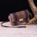 Vista detallada que muestra la textura de cocodrilo en un bolso bandolera de cuero degradado marrón. - Concha + Canela